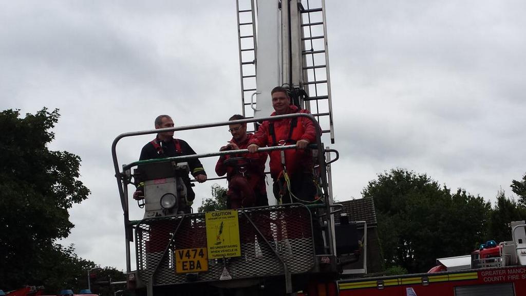 Team members Neil Aspinall and Mike Wakerley enjoy a ride on a GMFRS Aerial Ladder Platform at Irlam Fire Station open day